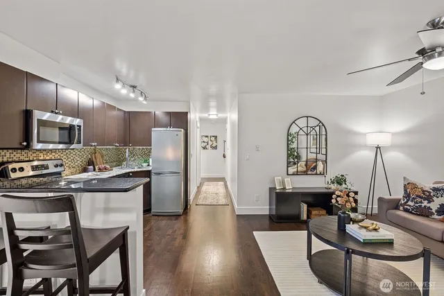 a kitchen with stainless steel appliances granite countertop a stove a refrigerator a kitchen island a dining table and chairs with wooden floor