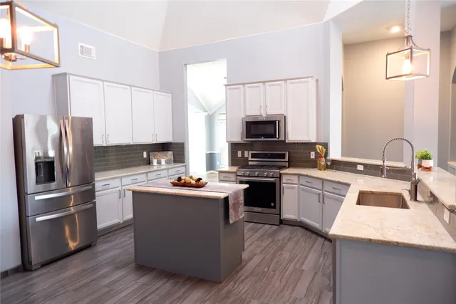 a kitchen with stainless steel appliances a sink dishwasher a refrigerator a stove top oven a sink and dishwasher with wooden floor