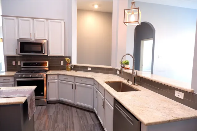 a kitchen with a sink dishwasher a stove and a microwave oven with wooden floor