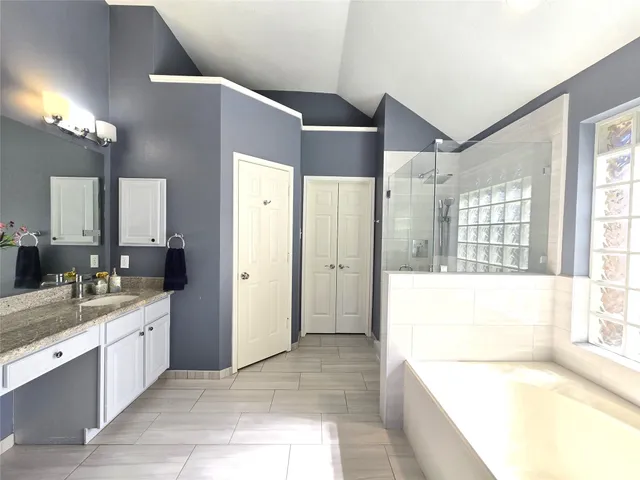 a spacious bathroom with a tub sink and mirror