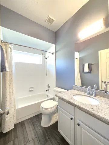 a bathroom with a granite countertop sink toilet a large mirror a bathtub and shower