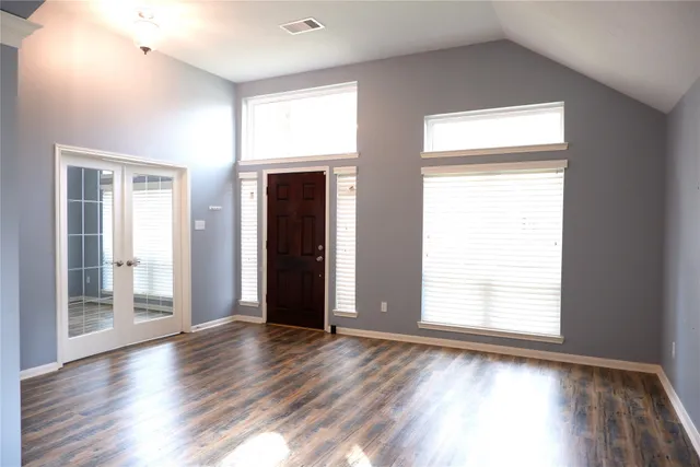 an empty room with wooden floor and windows