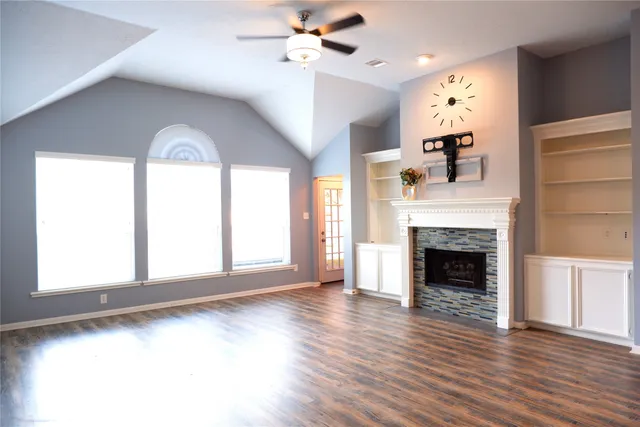 wooden floor fireplace and windows in an empty room