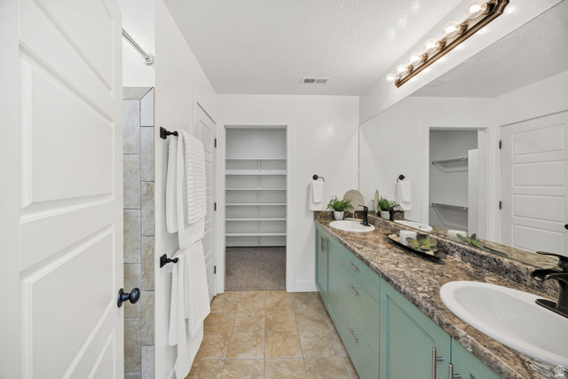 1552 Sumac Drive Logan, UT 84321 - Photo 24 of 72 Bathroom featuring a dual-sink vanity with a textured countertop and light blue cabinetry