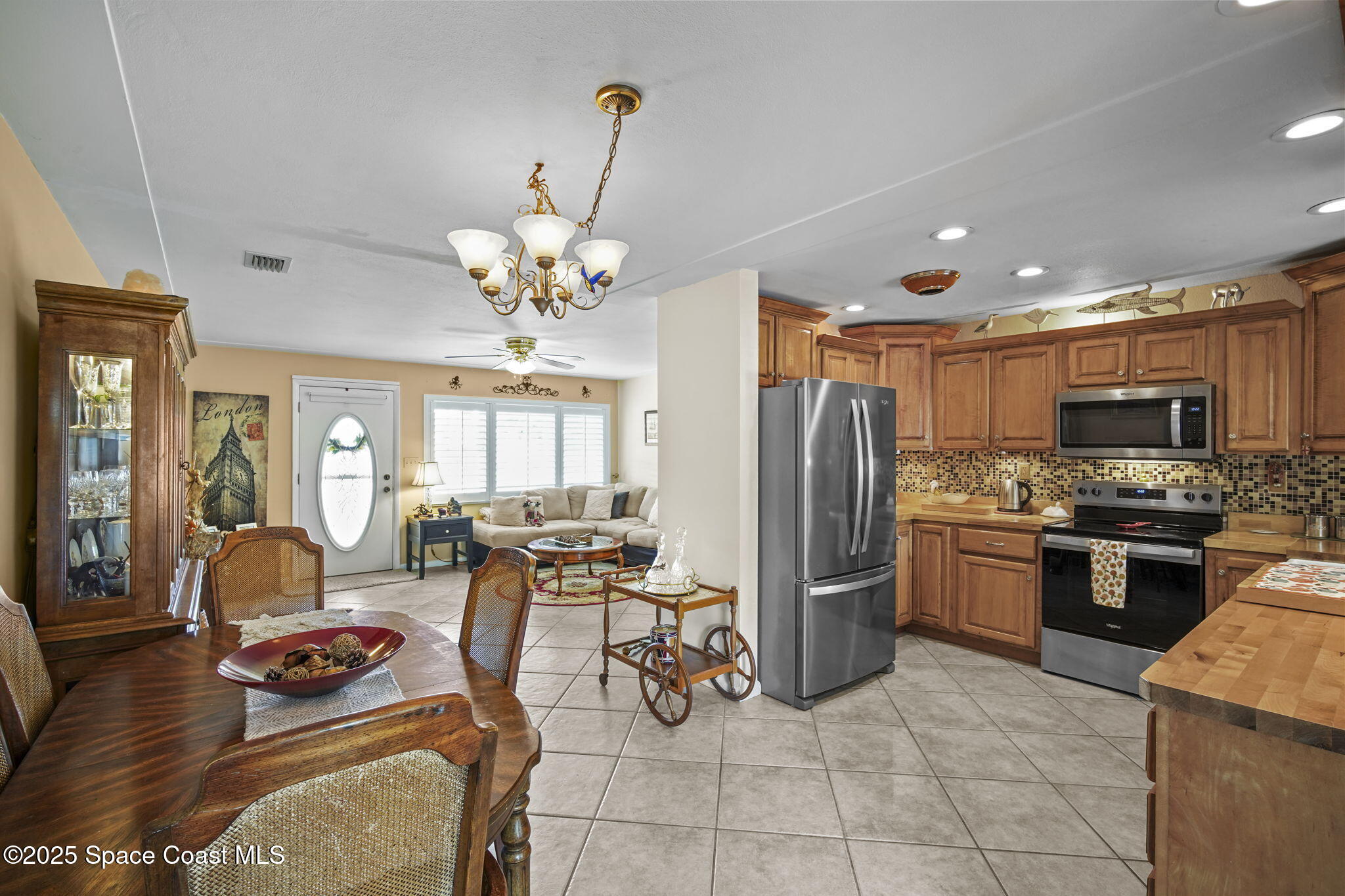 663 Bermuda Road Cocoa Beach, FL 32931 - Photo 11 of 51 a kitchen with stainless steel appliances granite countertop a refrigerator a sink dishwasher a stove and a dining table with wooden floor