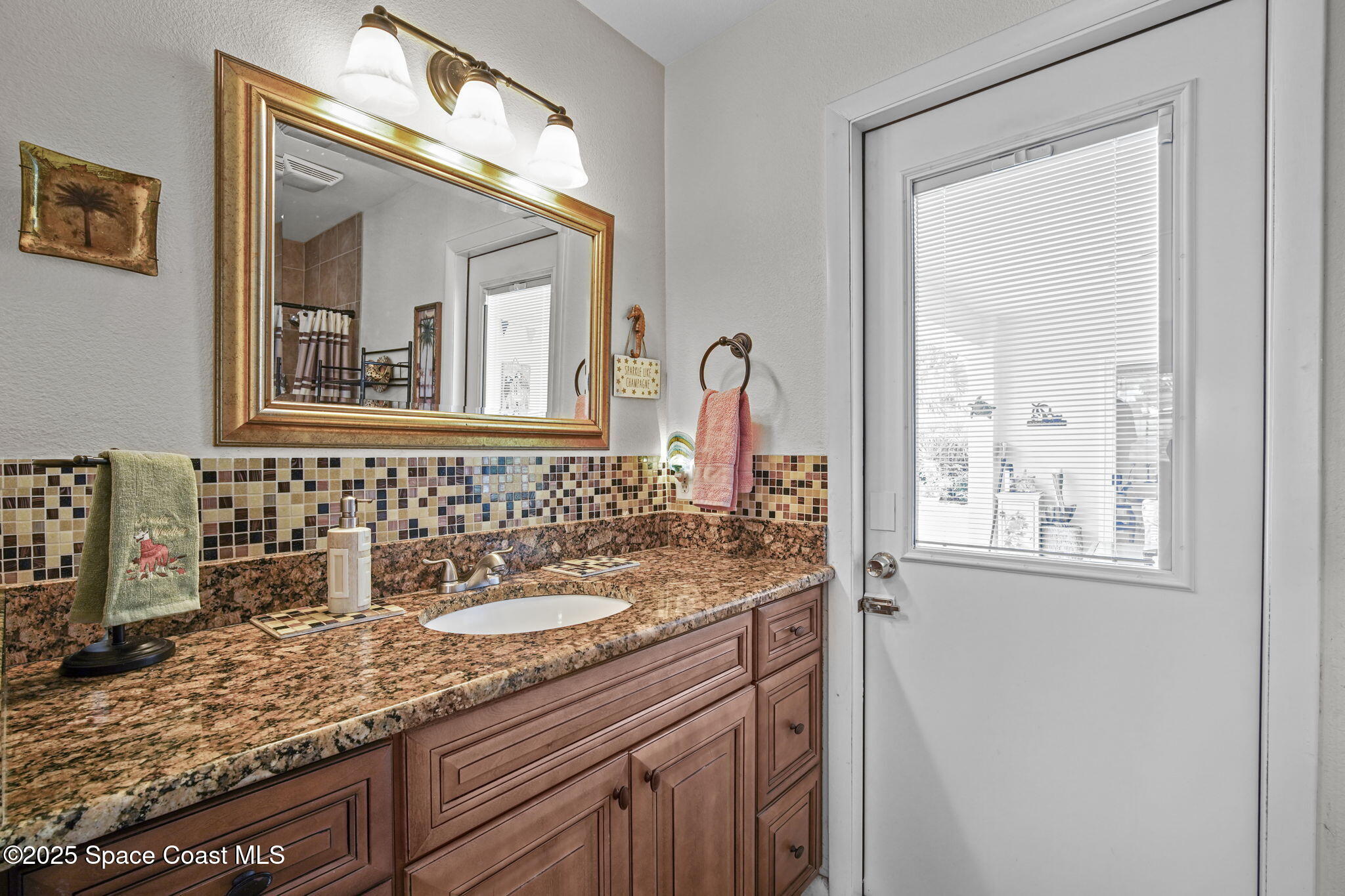 663 Bermuda Road Cocoa Beach, FL 32931 - Photo 20 of 51 a bathroom with a granite countertop sink a mirror and a window