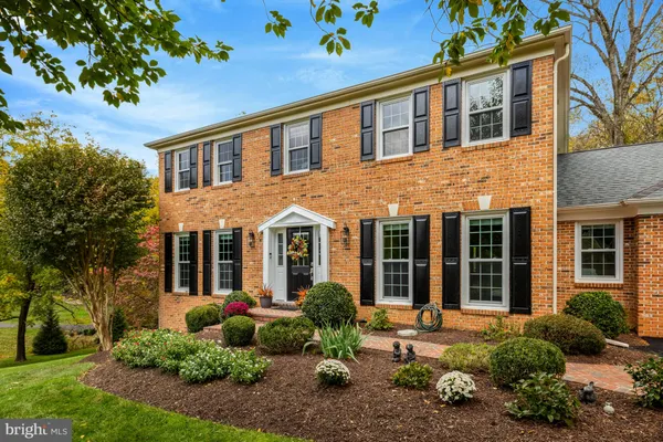 a front view of a house with a garden and trees