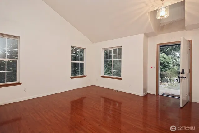 an empty room with wooden floor and windows