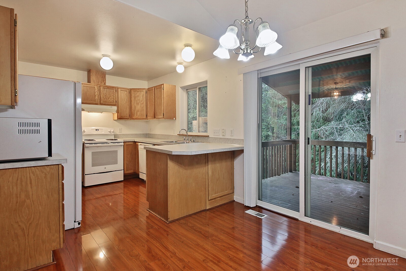 4369 Shadowood Drive Clinton, WA 98236 - Photo 21 of 37 a kitchen with stainless steel appliances granite countertop a stove a sink dishwasher a refrigerator and a dining table with wooden floor