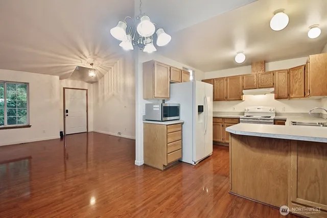 a kitchen with kitchen island stainless steel appliances a sink cabinets and wooden floor