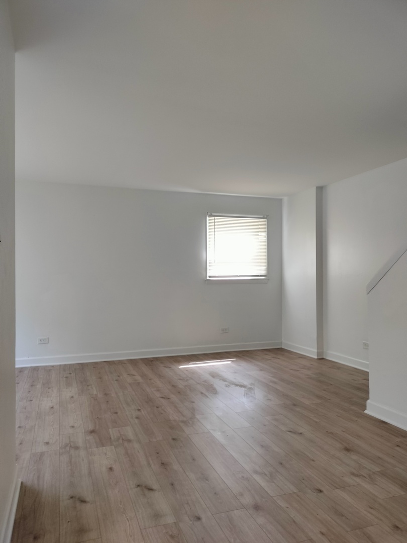 7910 South Muskegon Avenue, Unit 1 Chicago, IL 60617 - Photo 19 of 21 a view of an empty room with wooden floor and a window