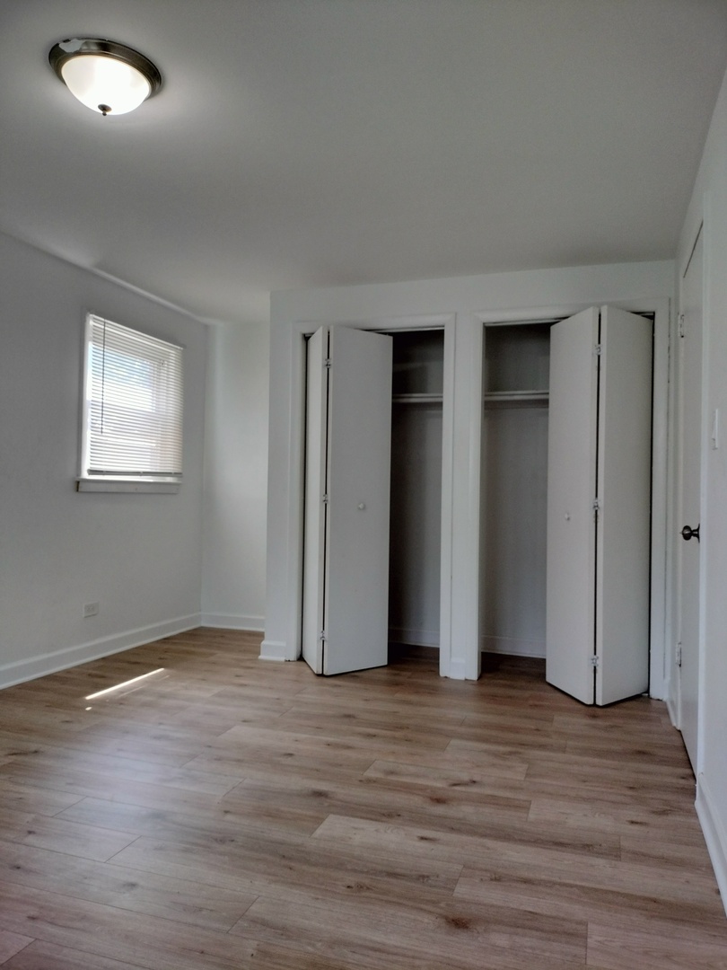 7910 South Muskegon Avenue, Unit 1 Chicago, IL 60617 - Photo 6 of 21 an empty room with wooden floor and windows