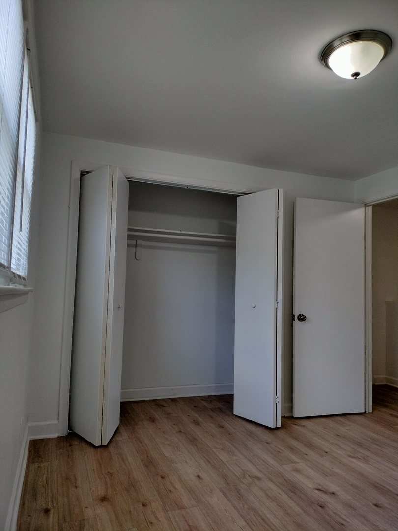 7910 South Muskegon Avenue, Unit 1 Chicago, IL 60617 - Photo 9 of 21 an empty room with wooden floor and windows