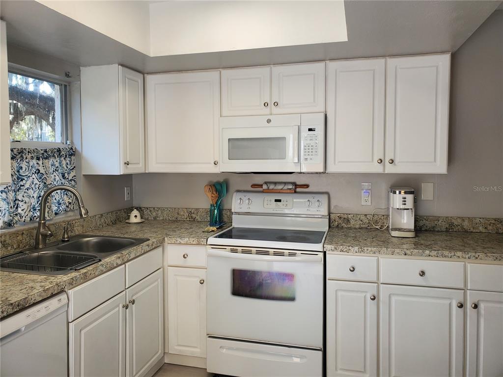 107 Springwood Square Port Orange, FL 32129 - Photo 16 of 36 a kitchen with granite countertop white cabinets sink and white appliances