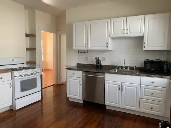 a kitchen with granite countertop white cabinets and white appliances