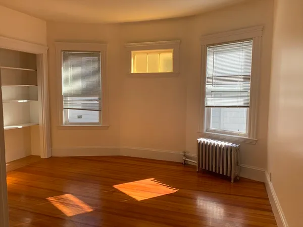 a view of an empty room with window and wooden floor