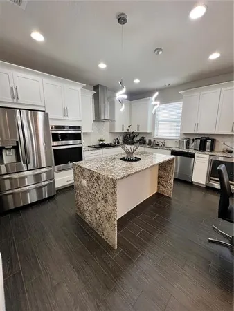 a kitchen with stainless steel appliances a stove a sink a oven a center island and chairs