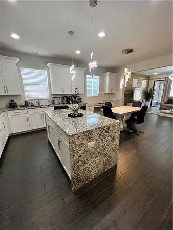 a large kitchen with kitchen island a large counter tops a stove a sink a dining table and chairs