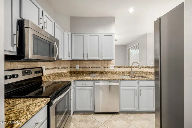 a kitchen with stainless steel appliances granite countertop a stove top oven a sink dishwasher and a refrigerator