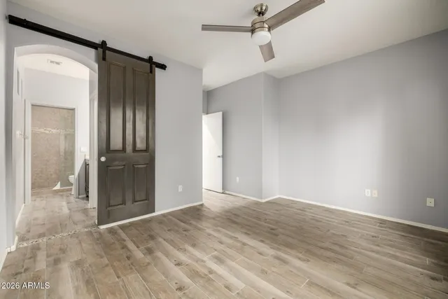 a view of an empty room with wooden floor and a bathroom