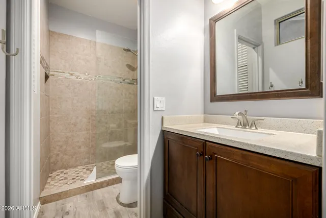 a bathroom with a granite countertop sink toilet a mirror and shower