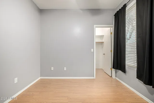 a view of an empty room with closet and a window