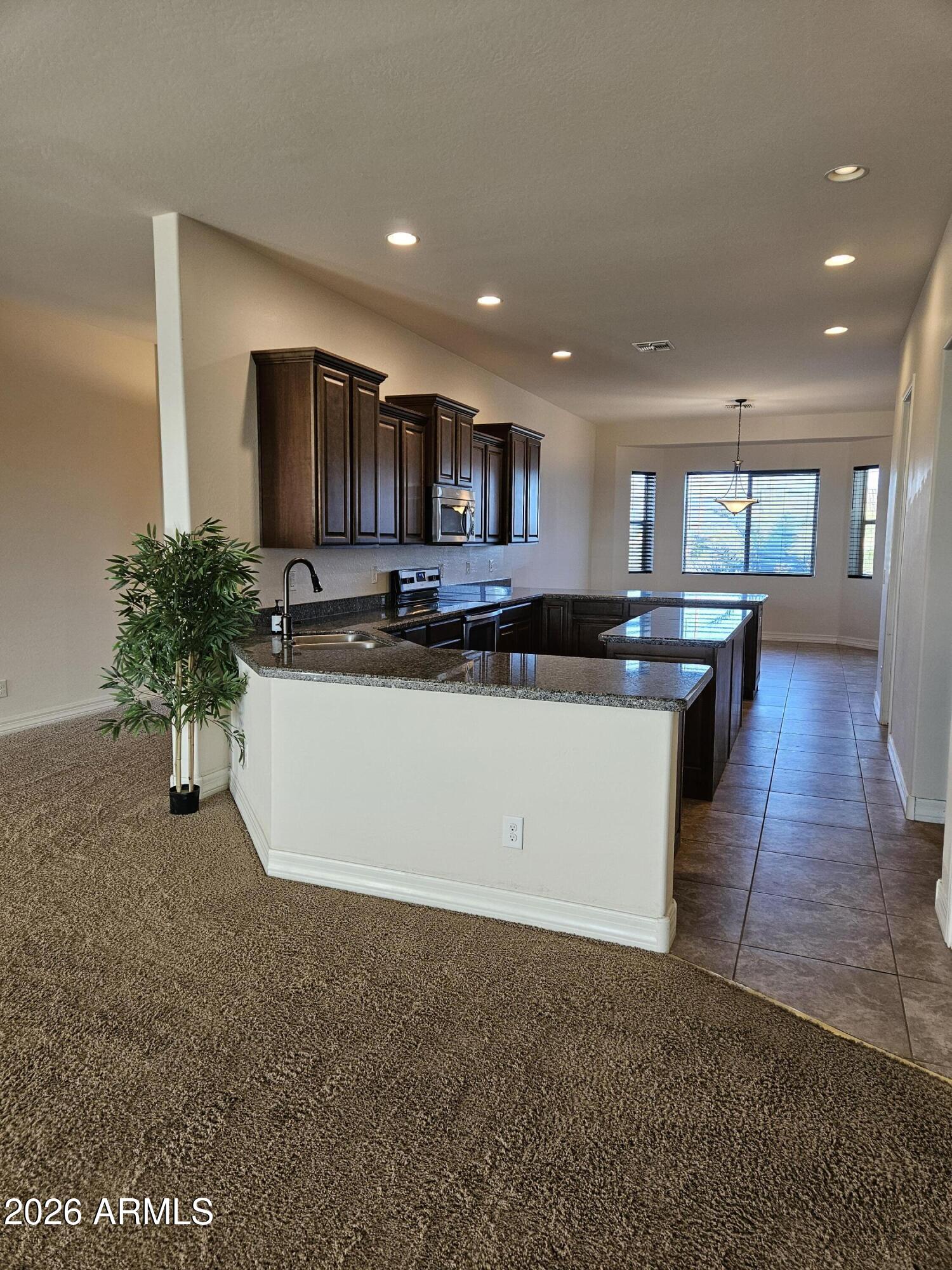 1623 East Hidalgo Street Apache Junction, AZ 85119 - Photo 8 of 65 a view of kitchen with stainless steel appliances kitchen island granite countertop a stove a sink a refrigerator and a dining table with wooden floor