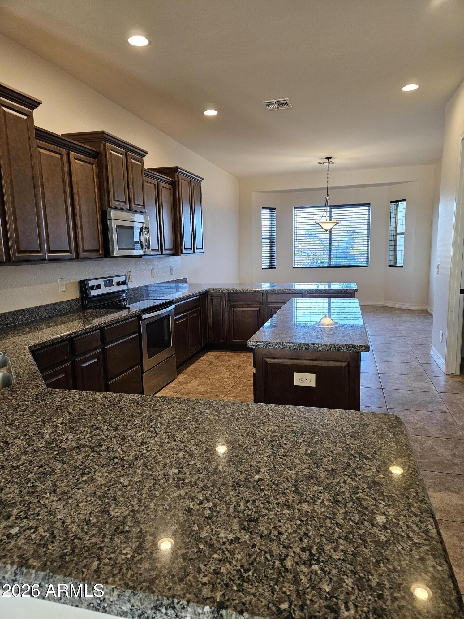 1623 East Hidalgo Street Apache Junction, AZ 85119 - Photo 9 of 65 a kitchen with stainless steel appliances granite countertop a sink a stove and a wooden cabinets