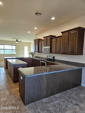 a kitchen with stainless steel appliances granite countertop a sink a stove top oven a counter space and cabinets