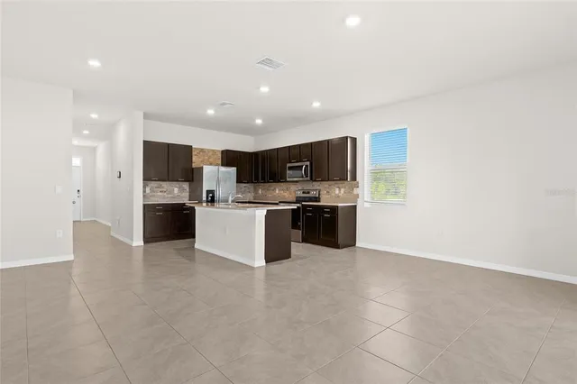 a large kitchen with stainless steel appliances granite countertop a large counter top and a stove top oven with wooden floor