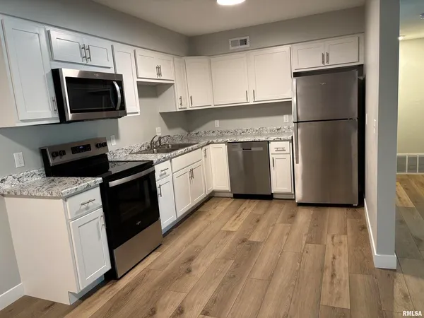 a kitchen with granite countertop a refrigerator stove and microwave