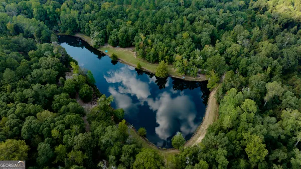 an aerial view of a house with outdoor space and trees all around