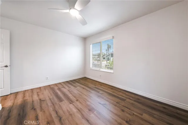 an empty room with wooden floor chandelier fan and windows