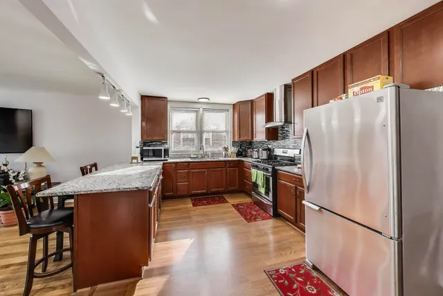a large kitchen with stainless steel appliances granite countertop a lot of counter space and wooden floor