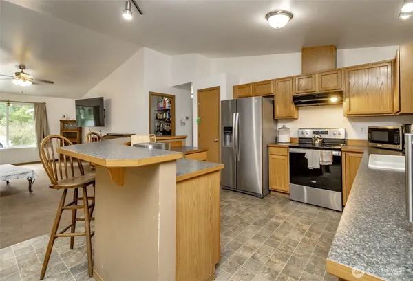 a kitchen with stainless steel appliances granite countertop a sink stove refrigerator and cabinets
