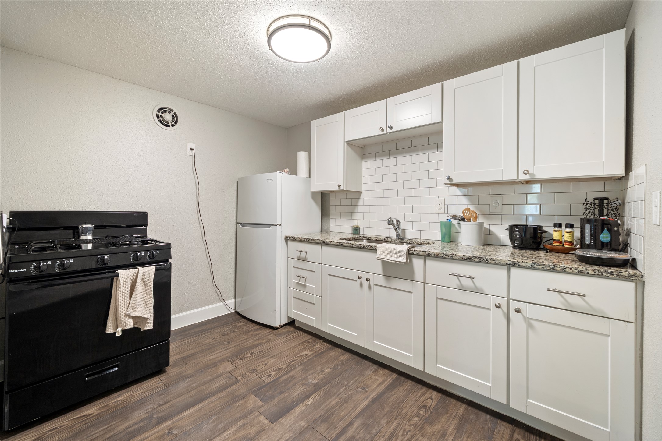 201 West 31st Street, Unit E Austin, TX 78705 - Photo 2 of 16 Prepare culinary creations in a well-appointed kitchen featuring stylish subway tile and durable granite counters.