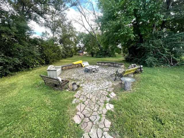 a view of a swimming pool with a bench and lawn chairs under an umbrella