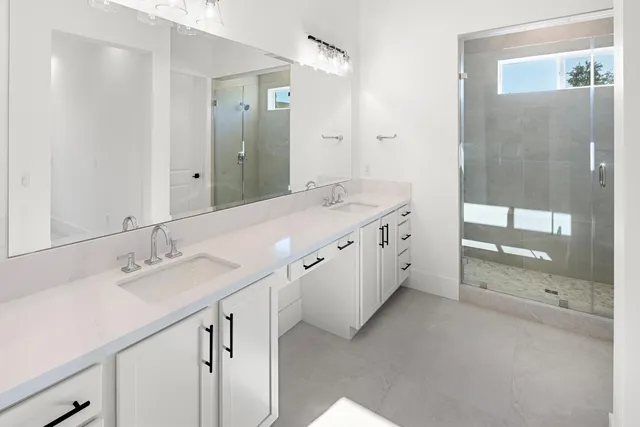 a spacious bathroom with a double vanity sink mirror and shower