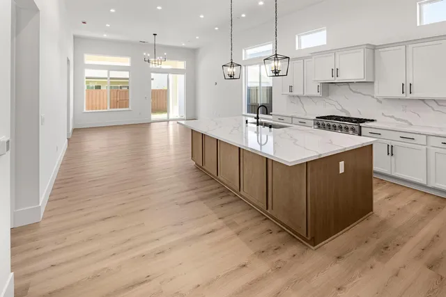 a kitchen with stainless steel appliances granite countertop a sink stove and white cabinets with wooden floor