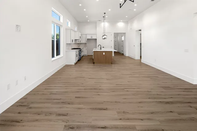 a view of kitchen with kitchen island a sink wooden floor and a refrigerator