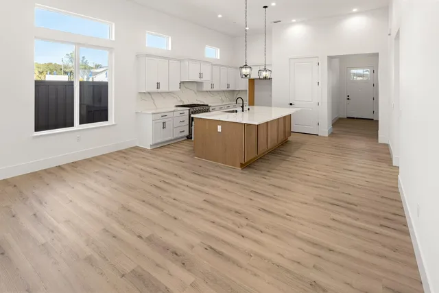 a large room with kitchen island a sink wooden floor and a large window