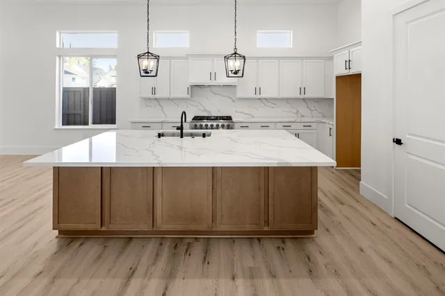 a large kitchen with wooden floor a sink and a refrigerator
