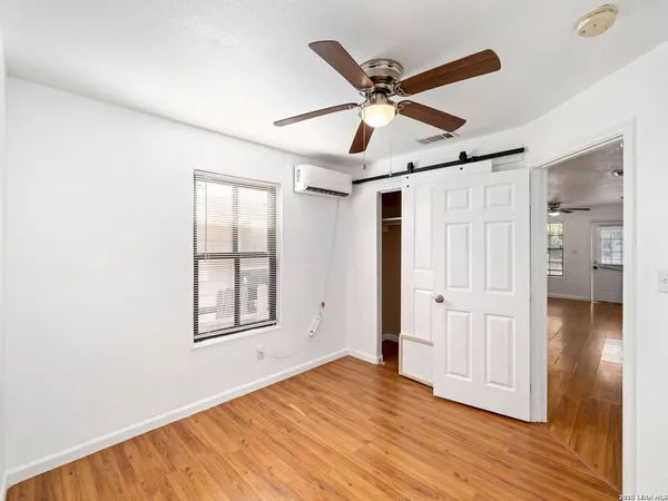 a view of empty room with wooden floor and fan