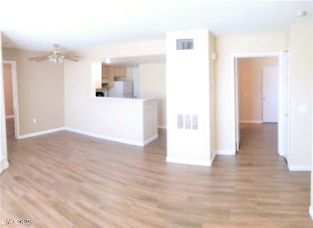 1830 North Pecos Road, Unit 131 Las Vegas, NV 89115 - Photo 6 of 13 Unfurnished living room with light wood-type flooring, baseboards, a ceiling fan, and visible vents