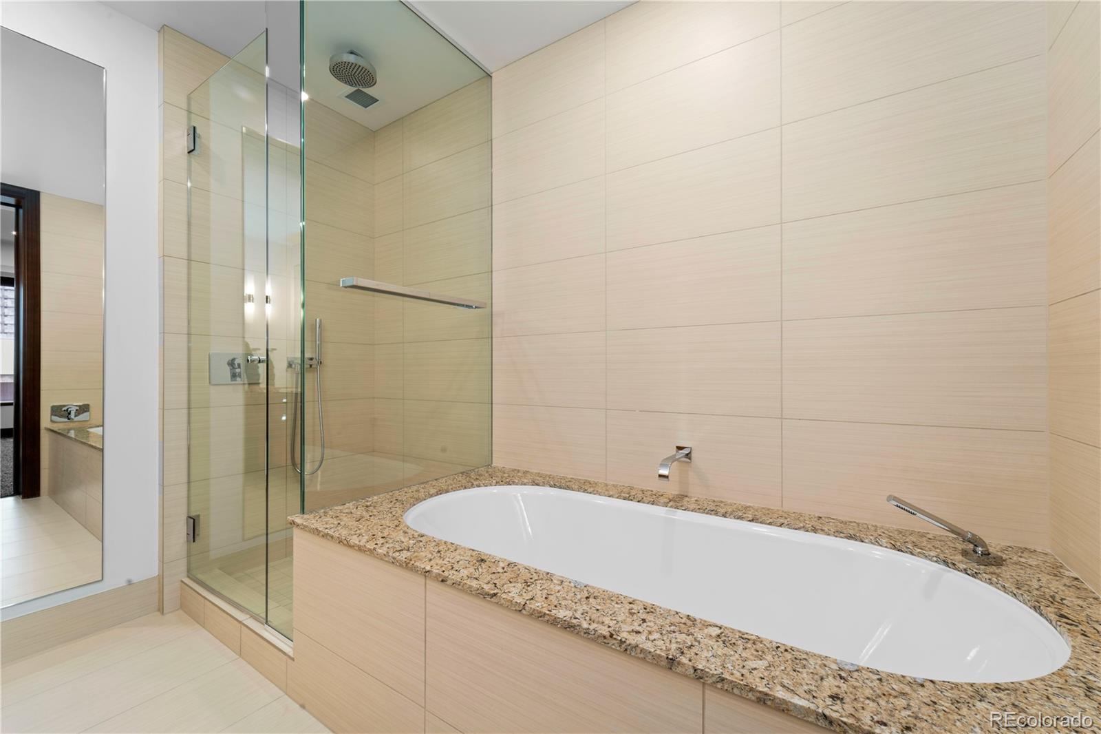 1133 14th Street, Unit 2620 Denver, CO 80202 - Photo 29 of 43 a bathroom with a granite countertop bathtub shower and sink