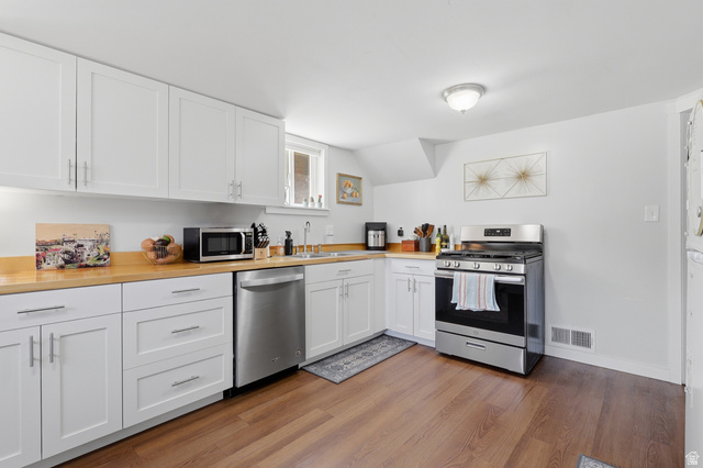 85 North 800 West Provo, UT 84601 - Photo 18 of 25 Kitchen featuring white shaker-style cabinetry with brushed nickel hardware, wood-finish countertops, stainless steel appliances, and wood-finish flooring