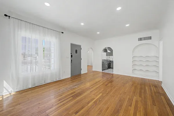 a view of empty room with wooden floor and window