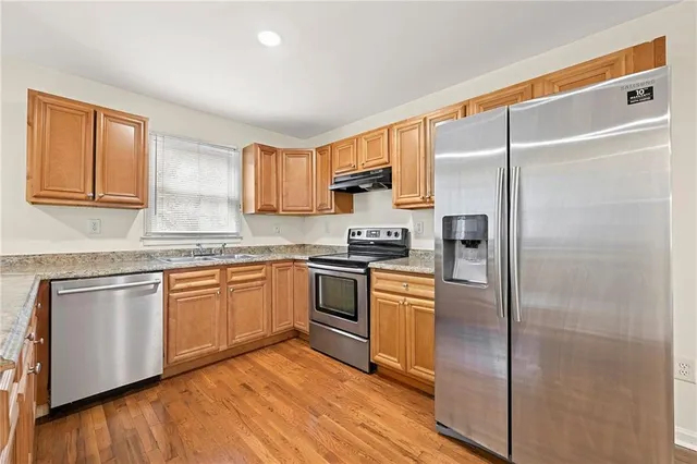 a kitchen with stainless steel appliances granite countertop a refrigerator and a stove top oven