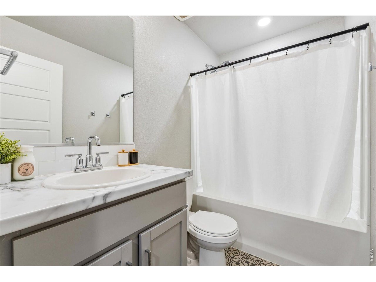 379 Beckwourth Avenue Fort Lupton, CO 80621 - Photo 17 of 26 a bathroom with a sink a toilet a mirror and shower curtain