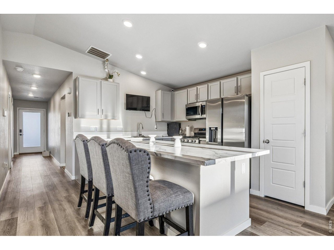 379 Beckwourth Avenue Fort Lupton, CO 80621 - Photo 6 of 26 a kitchen with stainless steel appliances kitchen island granite countertop a table chairs refrigerator and microwave